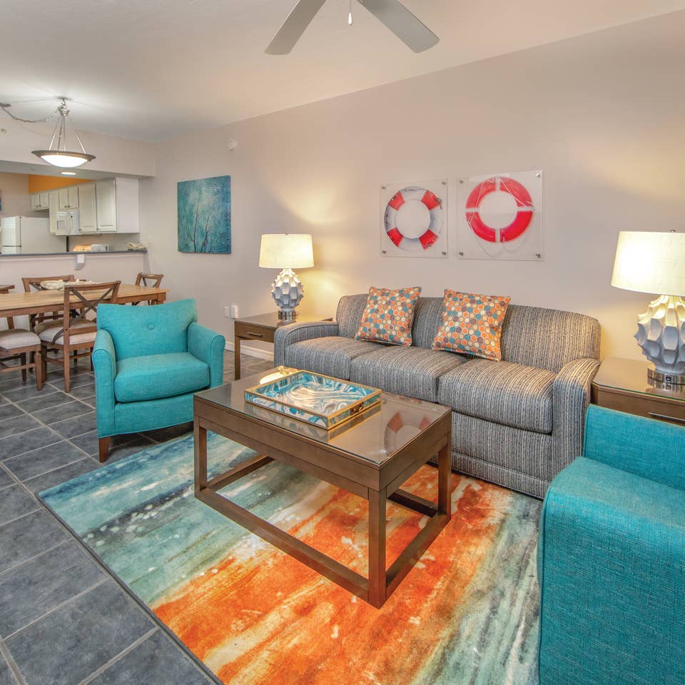 Living room with couch, two accent chairs, and coastal decor in a one-bedroom villa at Panama City Beach Resort