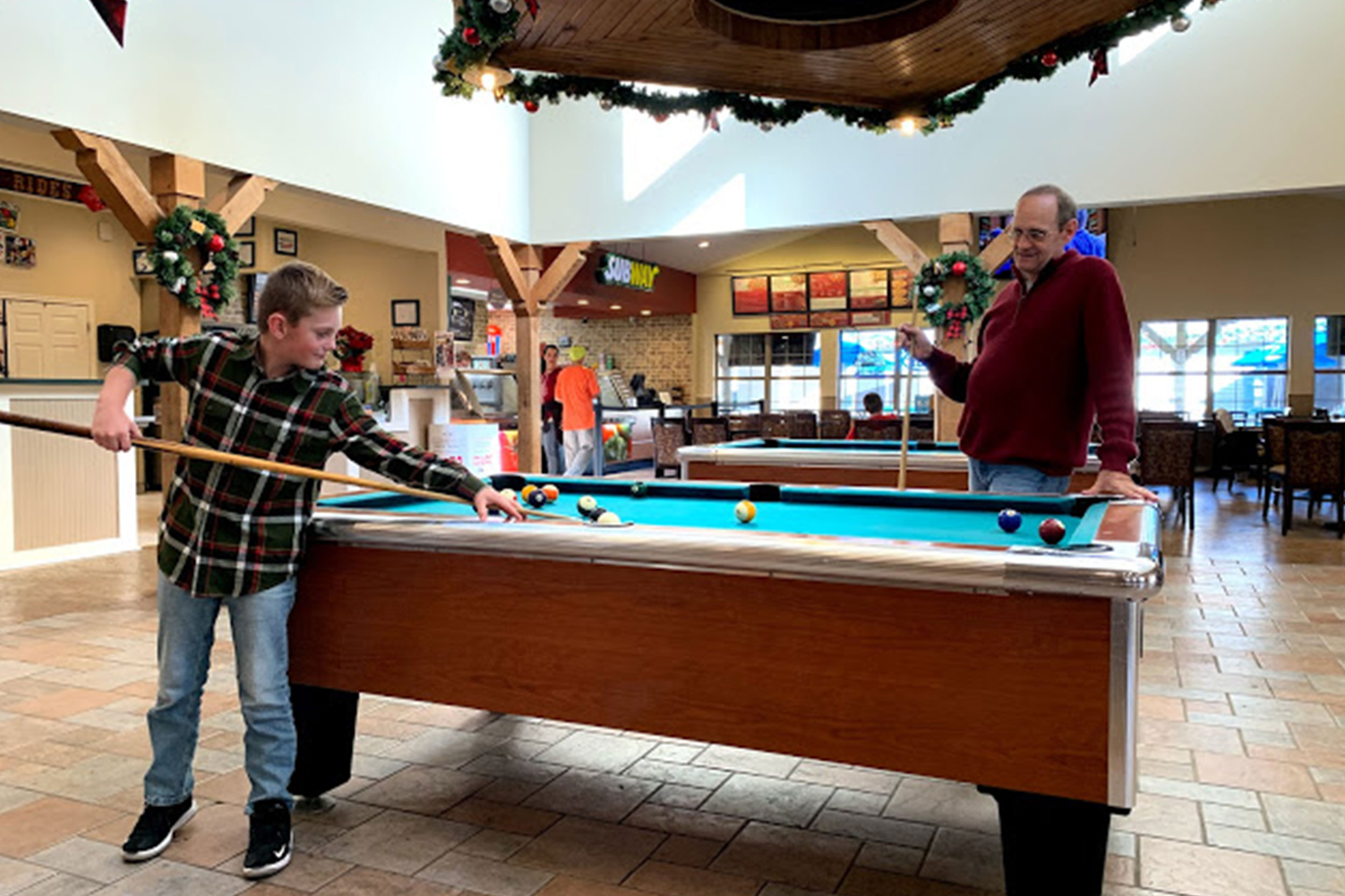 Amanda Nall's father (right) watches her son (left) play pool in the game room at the Villages Resort.