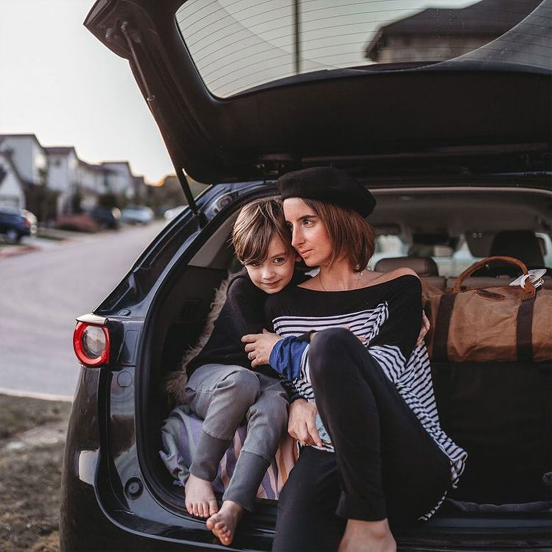 Featured Contributor, Eileen Lamb's son sits alongside her in the trunk of their black car surrounded by suitcases.