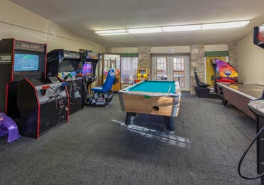 Game room with a pool table, air hockey table, and arcade games at Ozark Mountain Resort in Kimberling City, Missouri