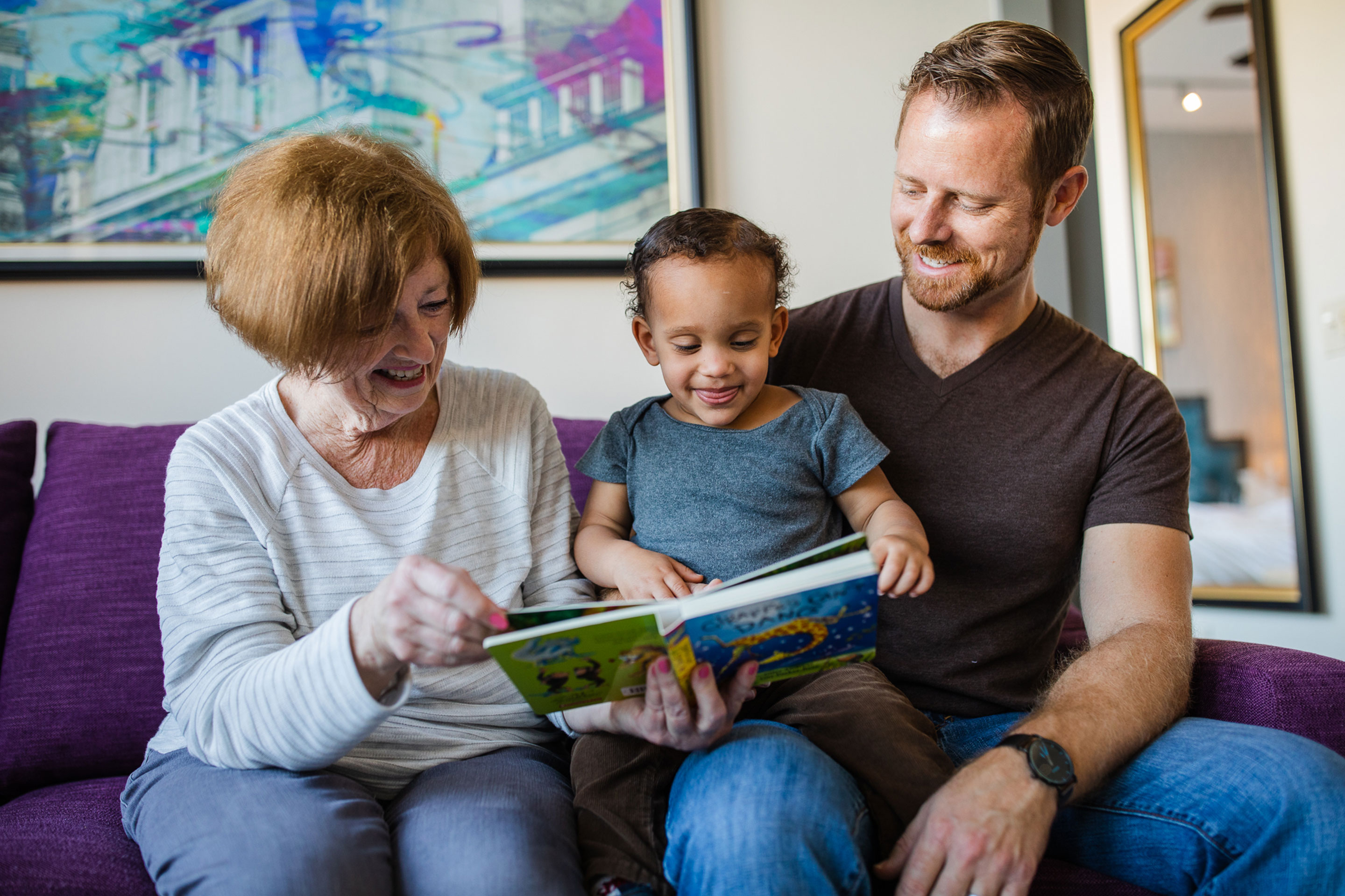 Featured Contributor, Sally Butan of @butanclan's husband (right) sits on a purple couch with his mother (left) as they read to his son (middle) at our Signature Collection villa in our resort in New Orleans, Louisiana.