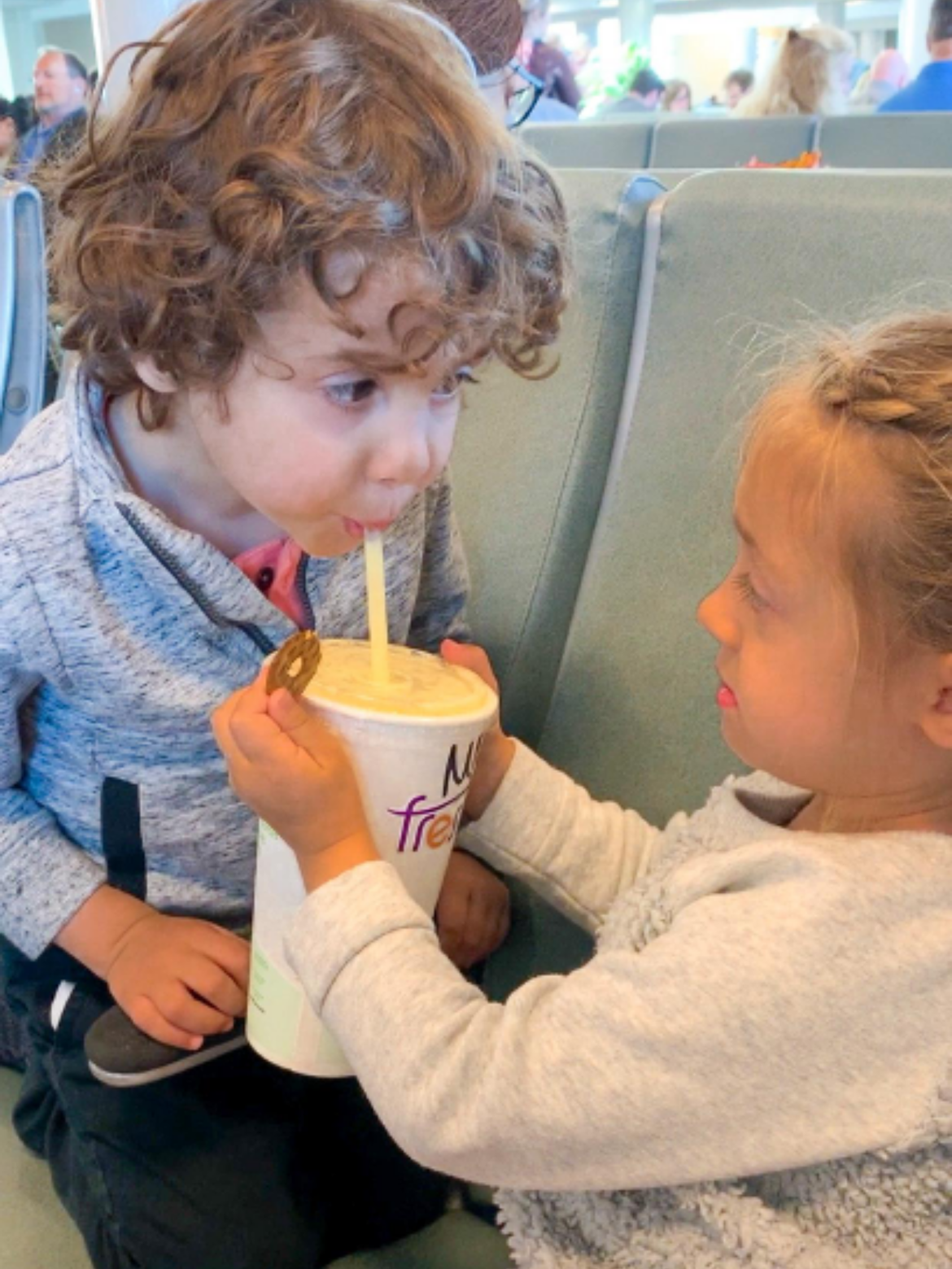 Raff's two kids drinking juice and eating snacks at the airport
