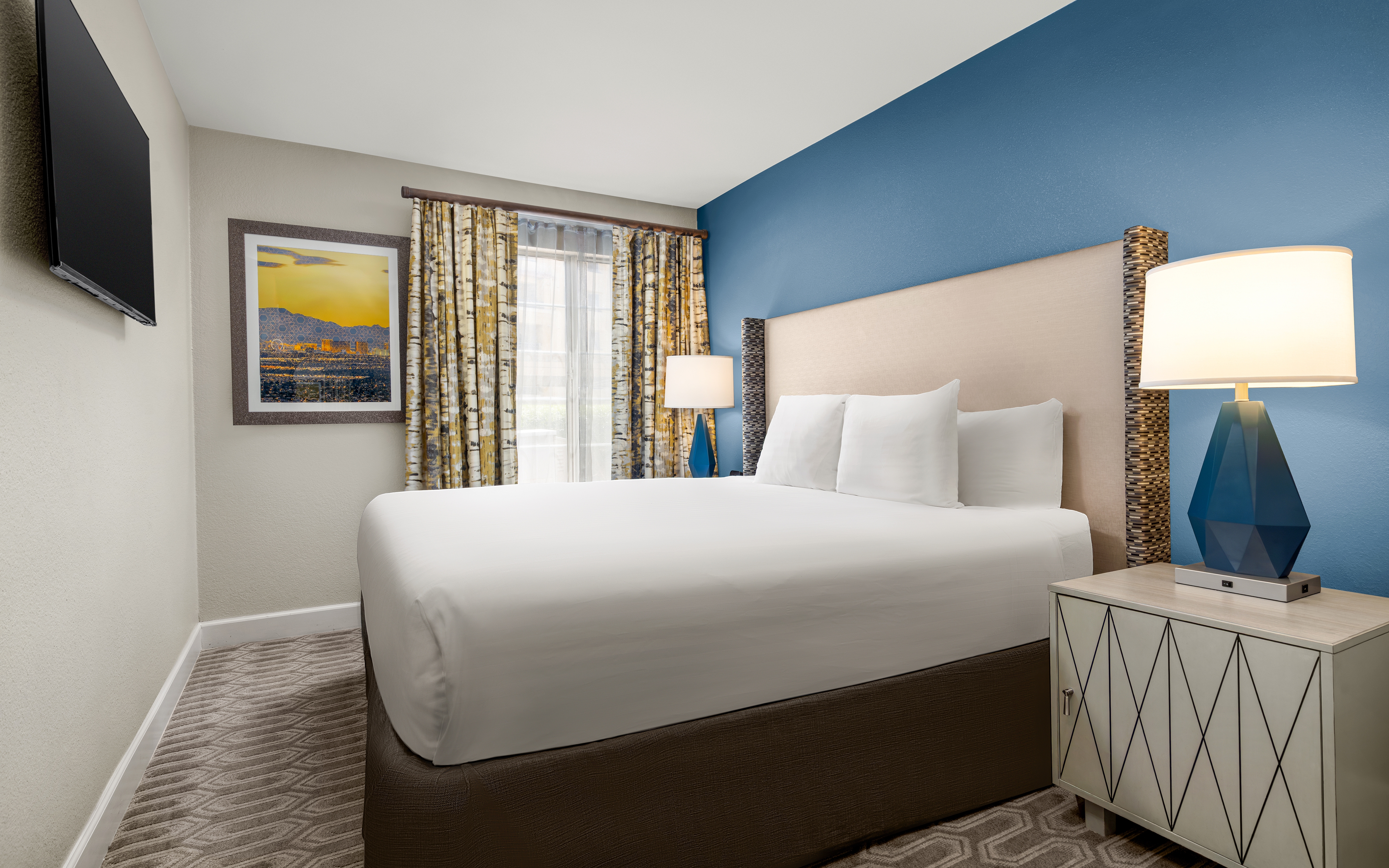 Bright bedroom with modern decor and blue accent wall.
