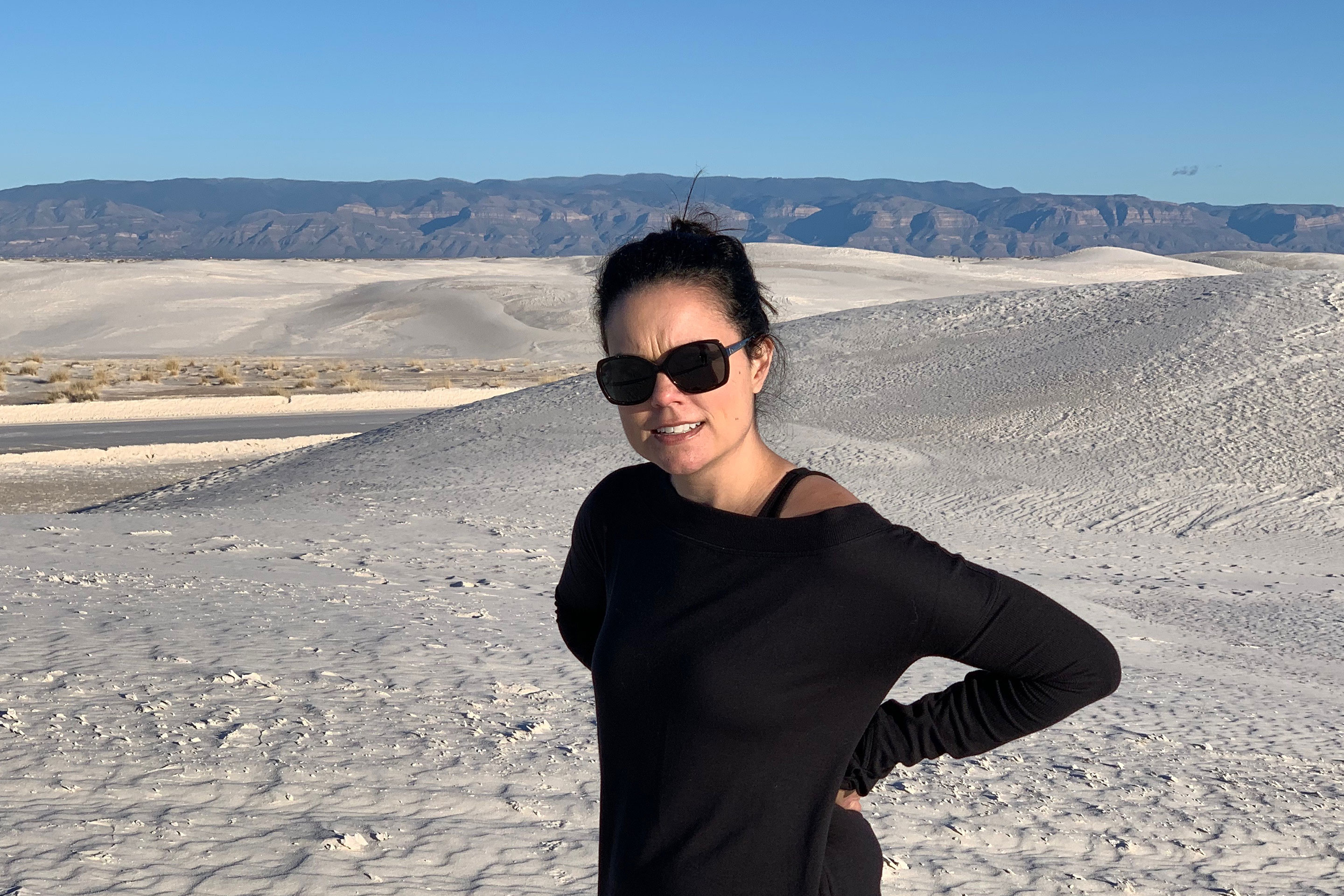 Author, Lauren Layne, stands looking frustrated at the White Sands National Monument.