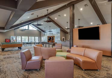 Game room with comfortable seating, a flat screen TV, pool tables, and ping pong tables at Piney Shores Resort in Conroe, Texas.