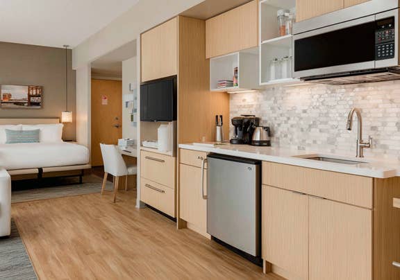 Stylish and bright hotel room offering spacious living area and kitchenette with modern amenities.