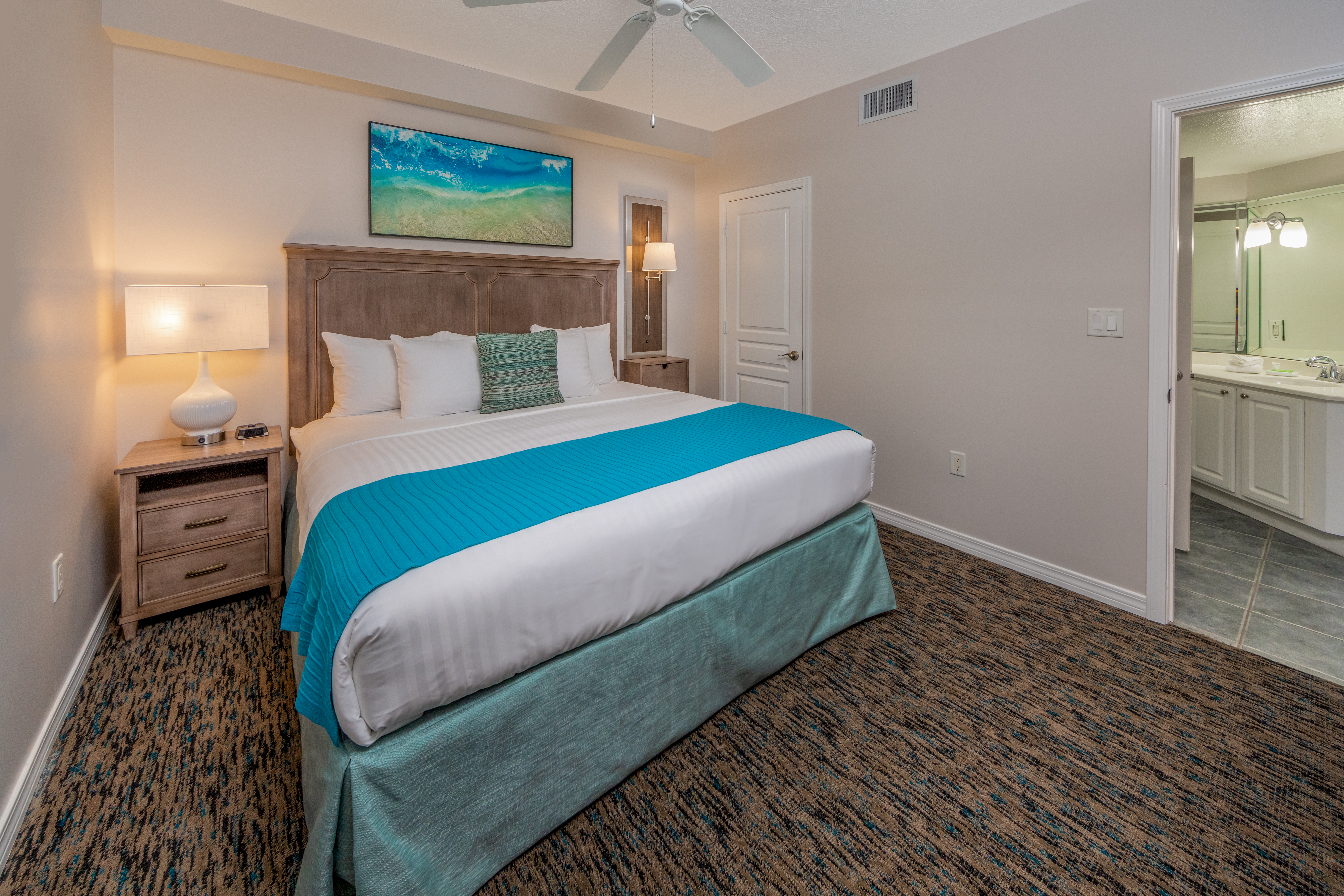Bedroom with attached bathroom and coastal decor in a one-bedroom villa at Panama City Beach Resort