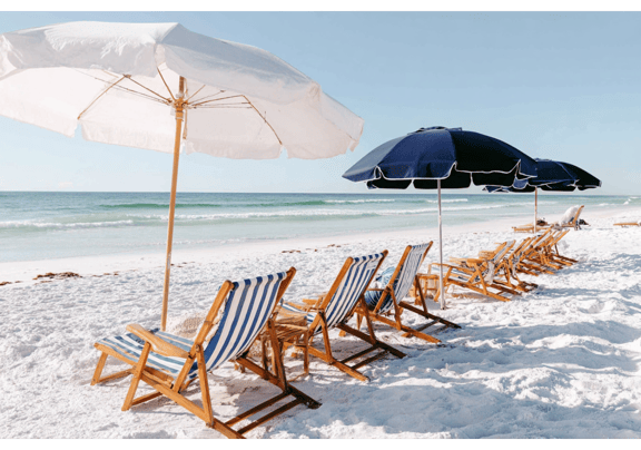 Striped beach chairs under white and navy umbrellas facing the ocean.