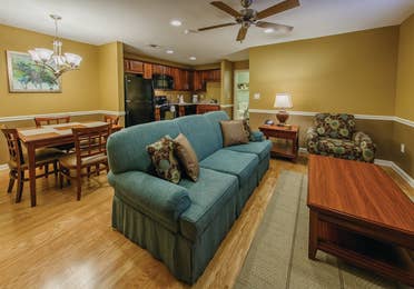 Living room couch with dining area in the background of a one-bedroom ambassador villa at the Hill Country Resort in Canyon Lake, Texas.