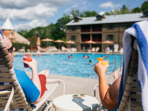 Two guests having drinks from the Tiki Bar by the pool at Oak n' Spruce Resort in South Lee, Massachusetts.