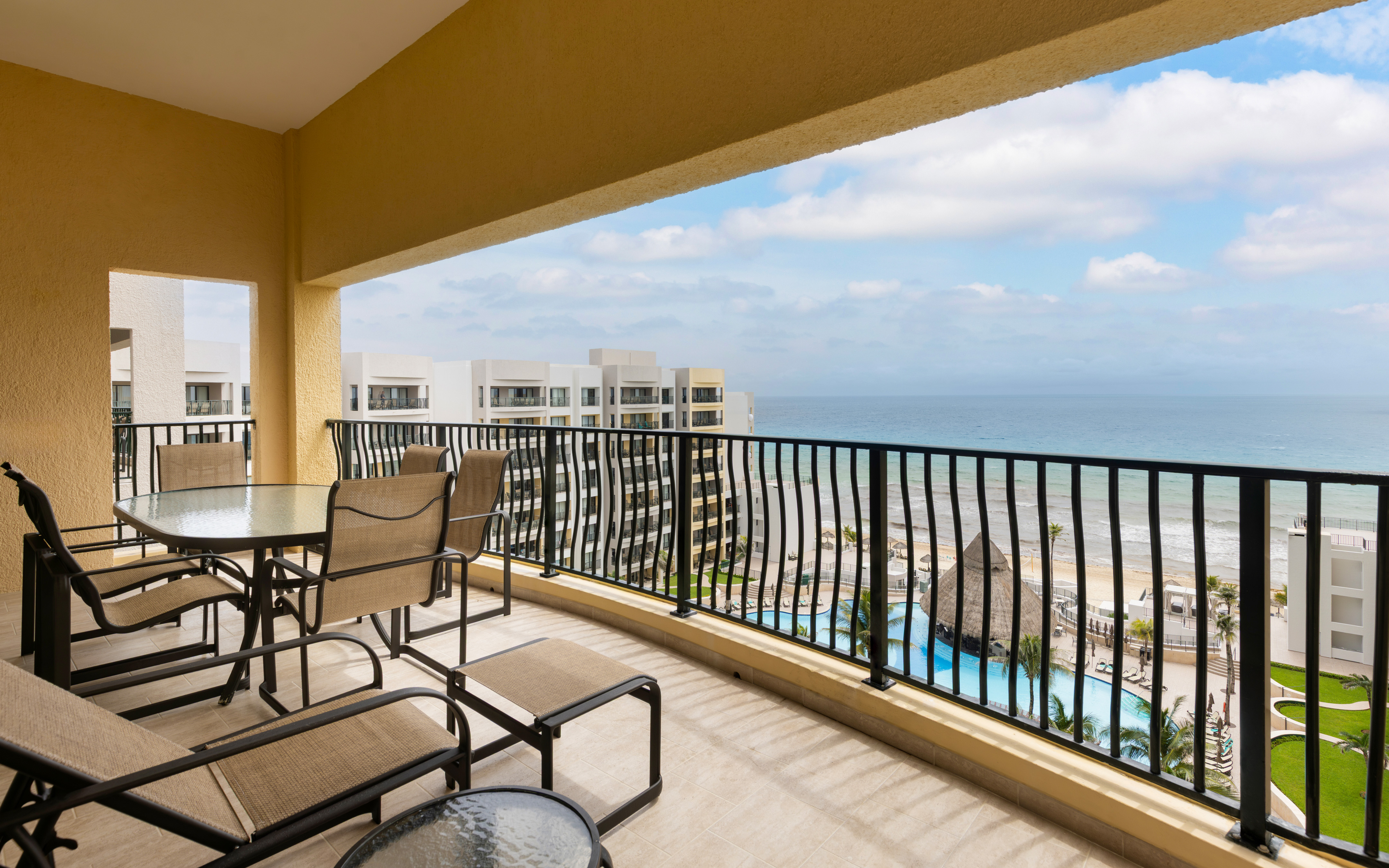 Spacious resort-view balcony with loungers and dining set. 