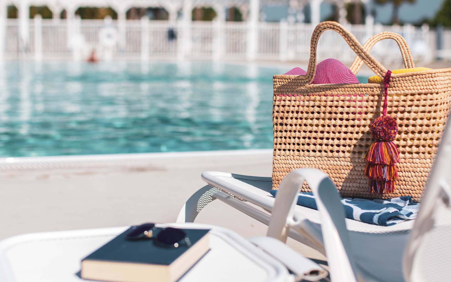 Pool bag, book and sunglasses sitting on pool chair by outdoor pool at Orlando Breeze Resort in Florida.