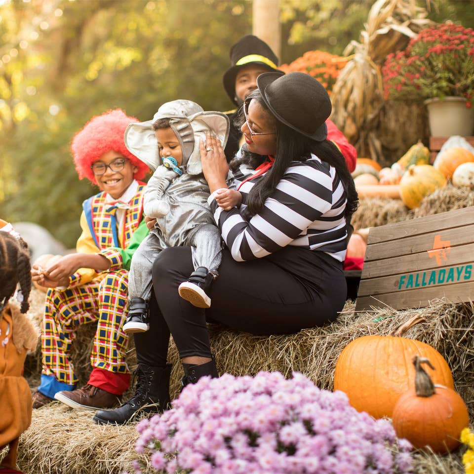 Family in costumes sitting on a pumpkin patch at the Villages Resort in Flint, TX