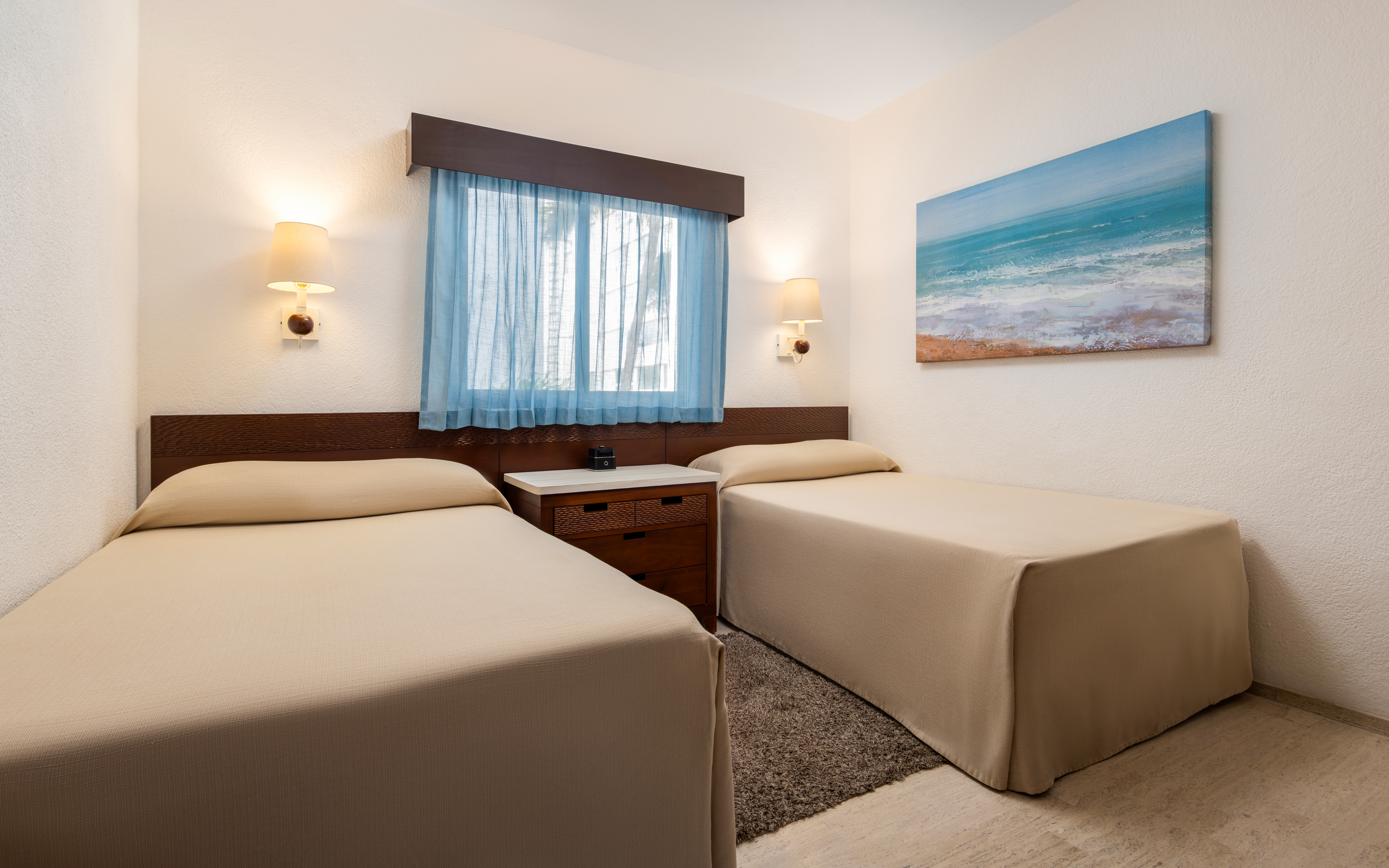 Modern bedroom with two twin beds, a window, and coastal artwork.