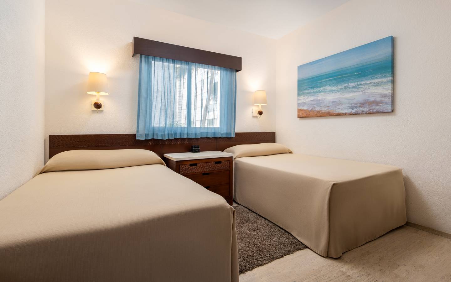 Modern bedroom with two twin beds, a window, and coastal artwork.