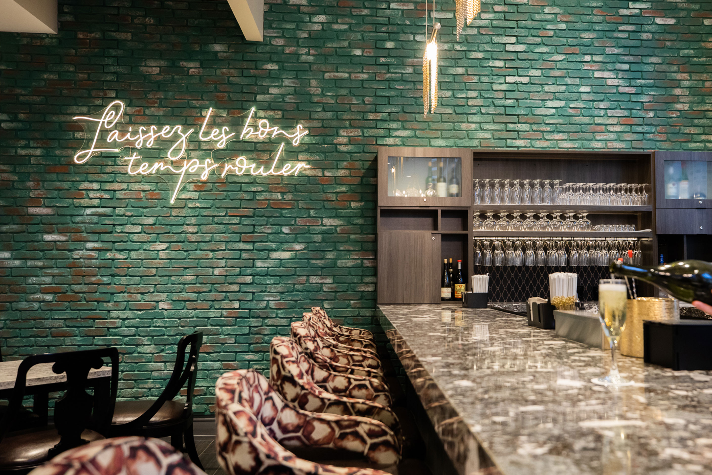 A green brick wall with a neon sign that reads, 'Laissez les bons temps rouler' featured in the Maritime Bar & Lounge at our resort in New Orleans, Louisiana.