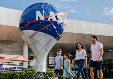 Family of four walking past NASA globe at the Kennedy Space Center℠ Visitor Complex.