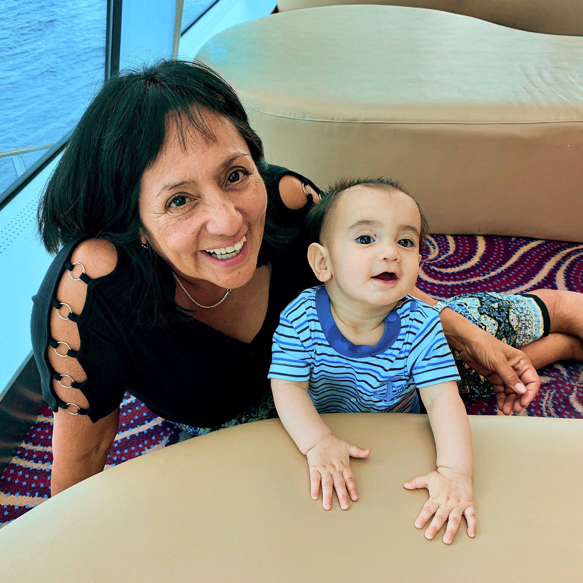 A woman and an infant sit on the deck of a boat.