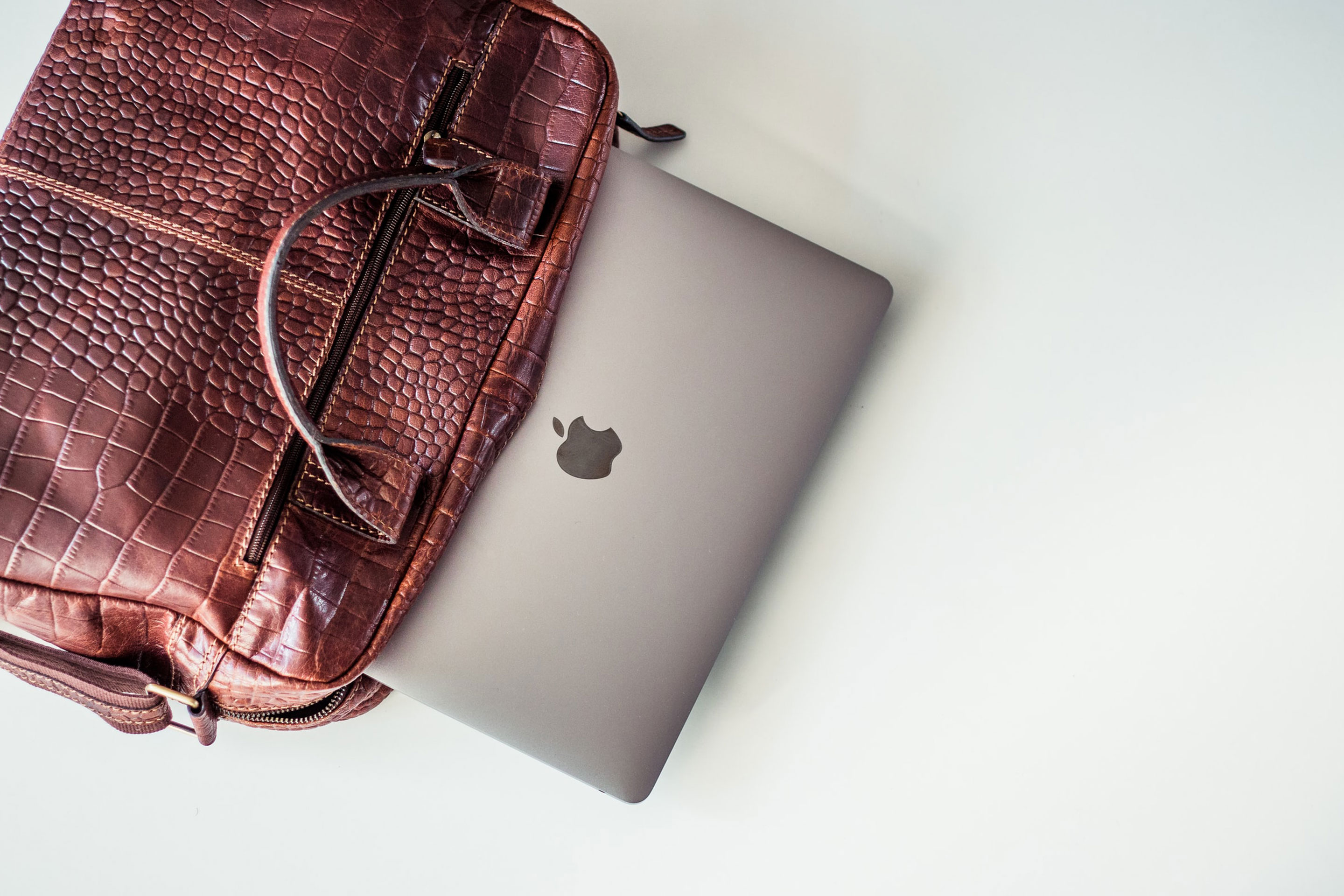 Laptop being removed from work bag over a white table.