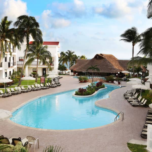 Outdoor pool surrounded by pool chairs and palm trees at the Royal Cancun Resort in Cancun, Mexico.
