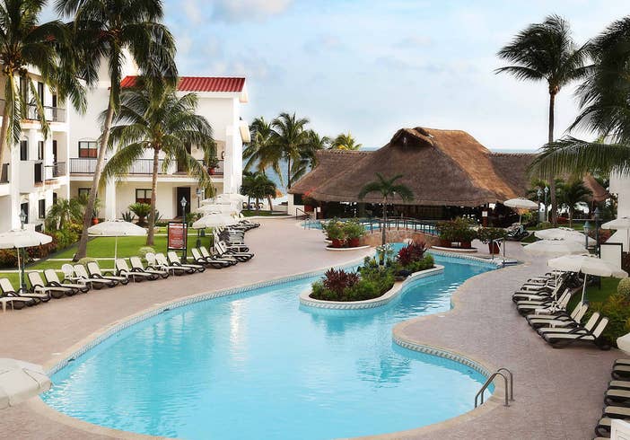 Outdoor pool surrounded by pool chairs and palm trees at the Royal Cancun Resort in Cancun, Mexico.