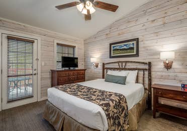 Bedroom with flat screen TV and ceiling fan in a two bedroom cabin at Piney Shores Resort in Conroe, Texas