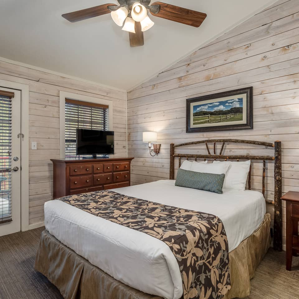 Bedroom with flat screen TV and ceiling fan in a two bedroom cabin at Piney Shores Resort in Conroe, Texas