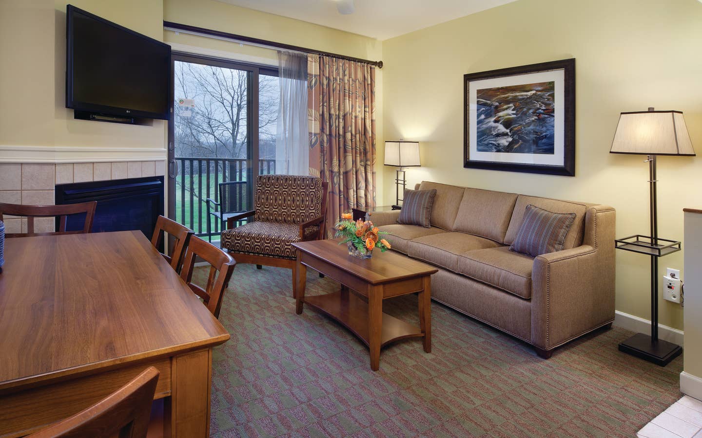 Living room with couch, accent chair, fireplace and flat screen TV in a villa at Lake Geneva Resort