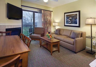 Living room with couch, accent chair, fireplace and flat screen TV in a villa at Lake Geneva Resort