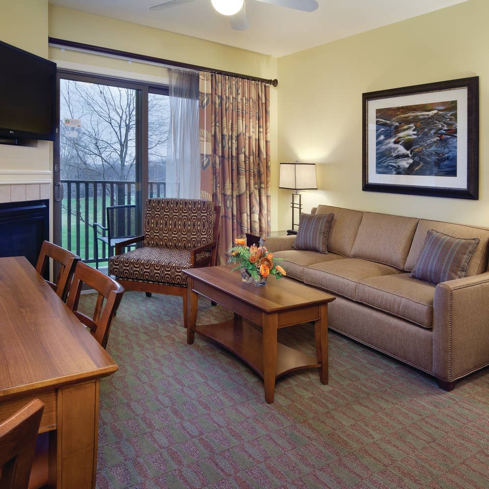 Living room with couch, accent chair, fireplace and flat screen TV in a villa at Lake Geneva Resort