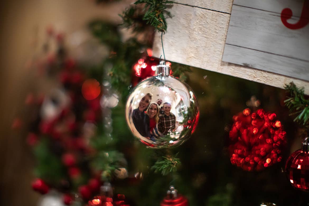 The Nall family look into a silver ornaments reflection as it hangs from a christmas tree.