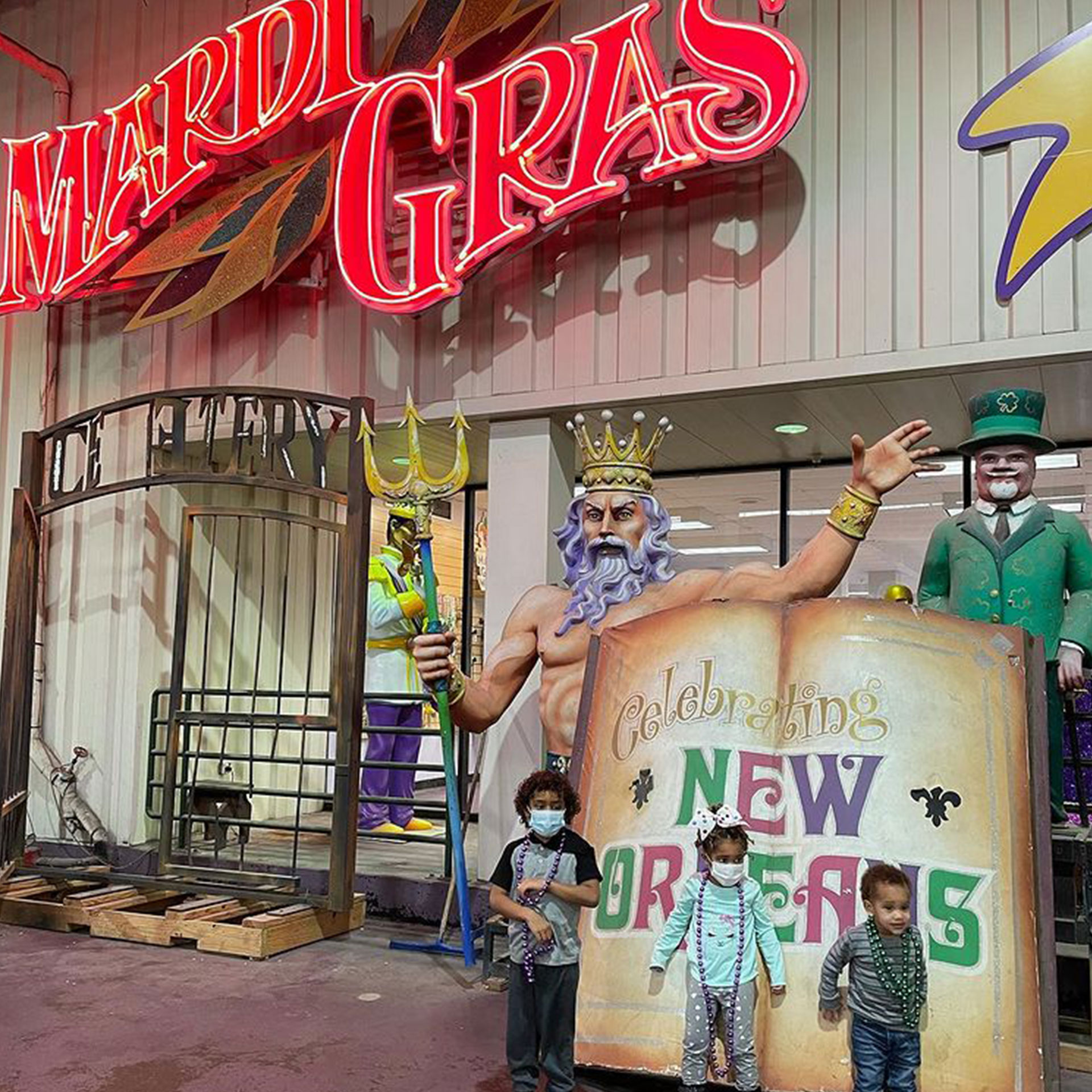 Featured Contributor, Sally Butan of @butanclan's daughter, Alissa (middle), and sons, Alex (left) and Alston (right) pose next to a giant book prop that reads, 'Celebrating New Orleans' outside of  Mardi Gras World in New Orleans, Louisiana.