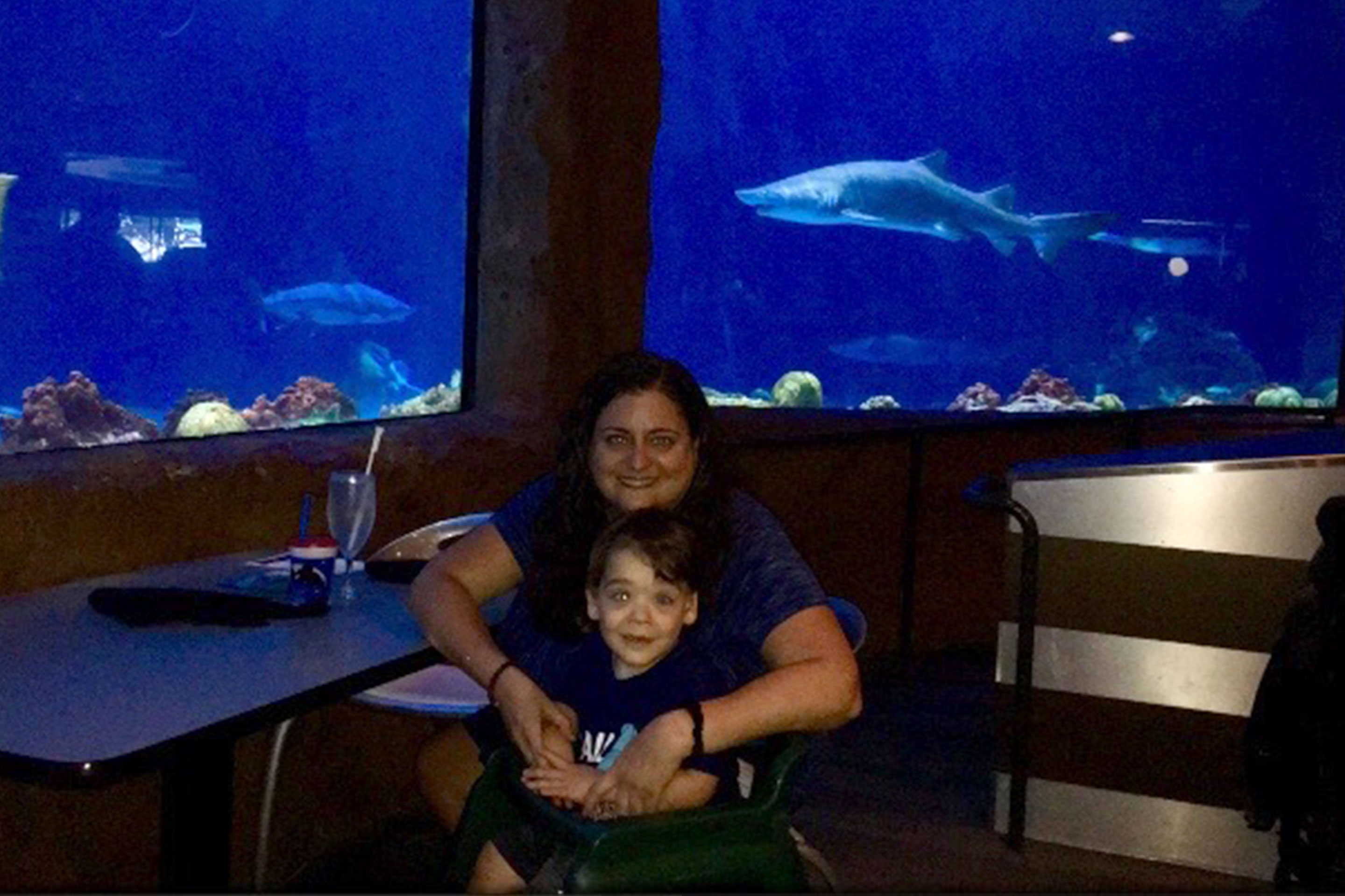 Theresa and Dakota are seated in front of an aquarium to view sharks while dining.