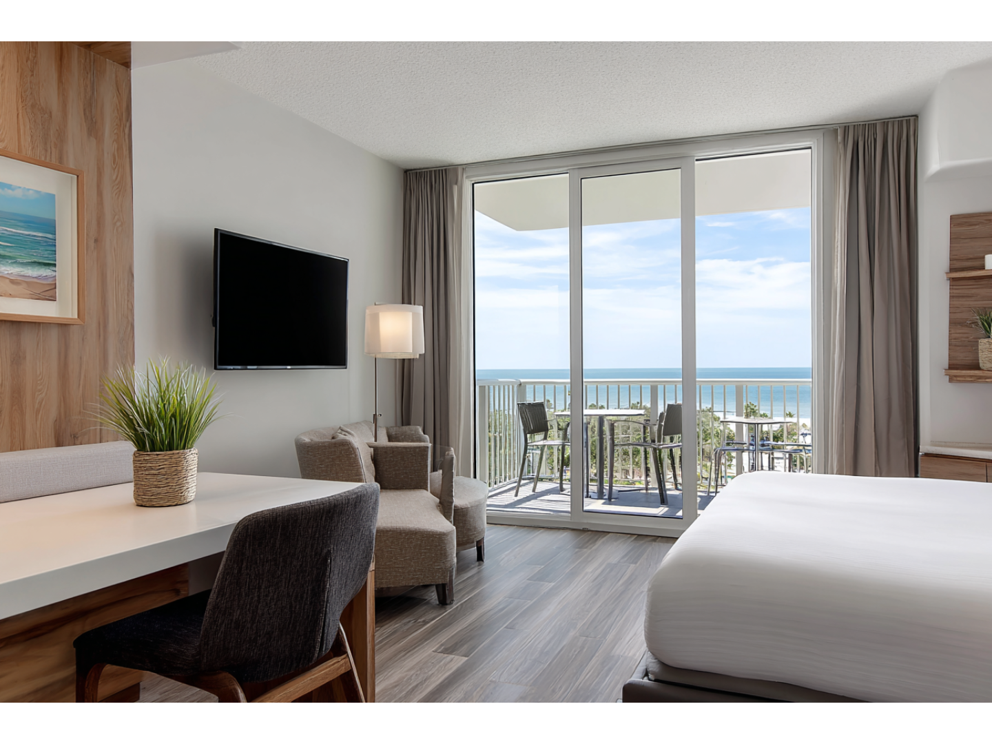 Modern hotel room with a private balcony offering a stunning view of the ocean.