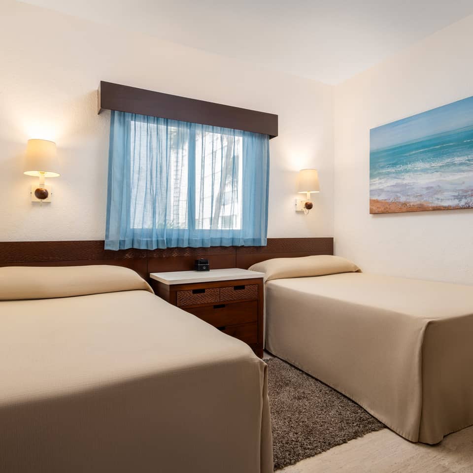 Modern bedroom with two twin beds, a window, and coastal artwork.