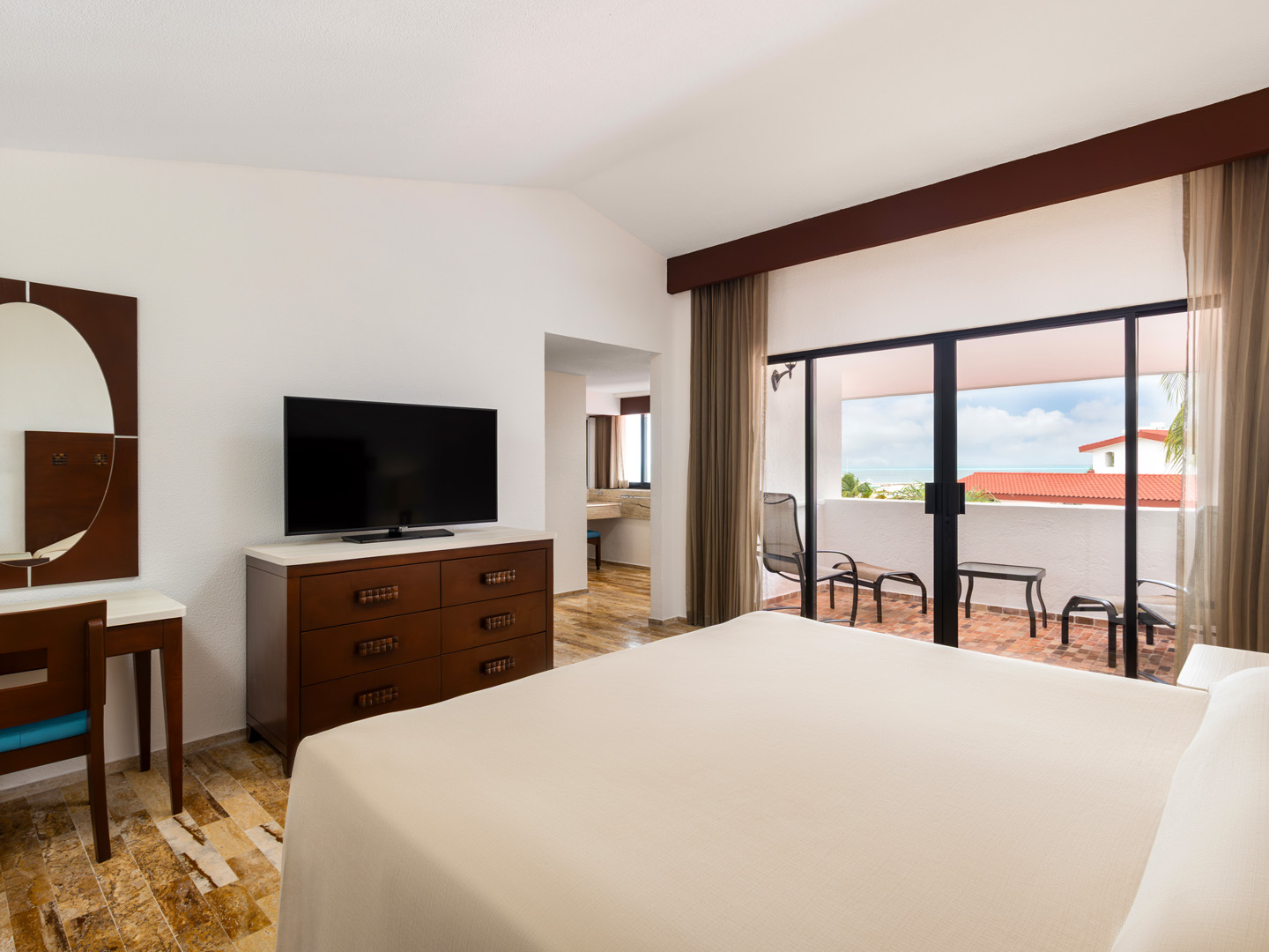 Suite bedroom with king bed and balcony overlooking gardens.