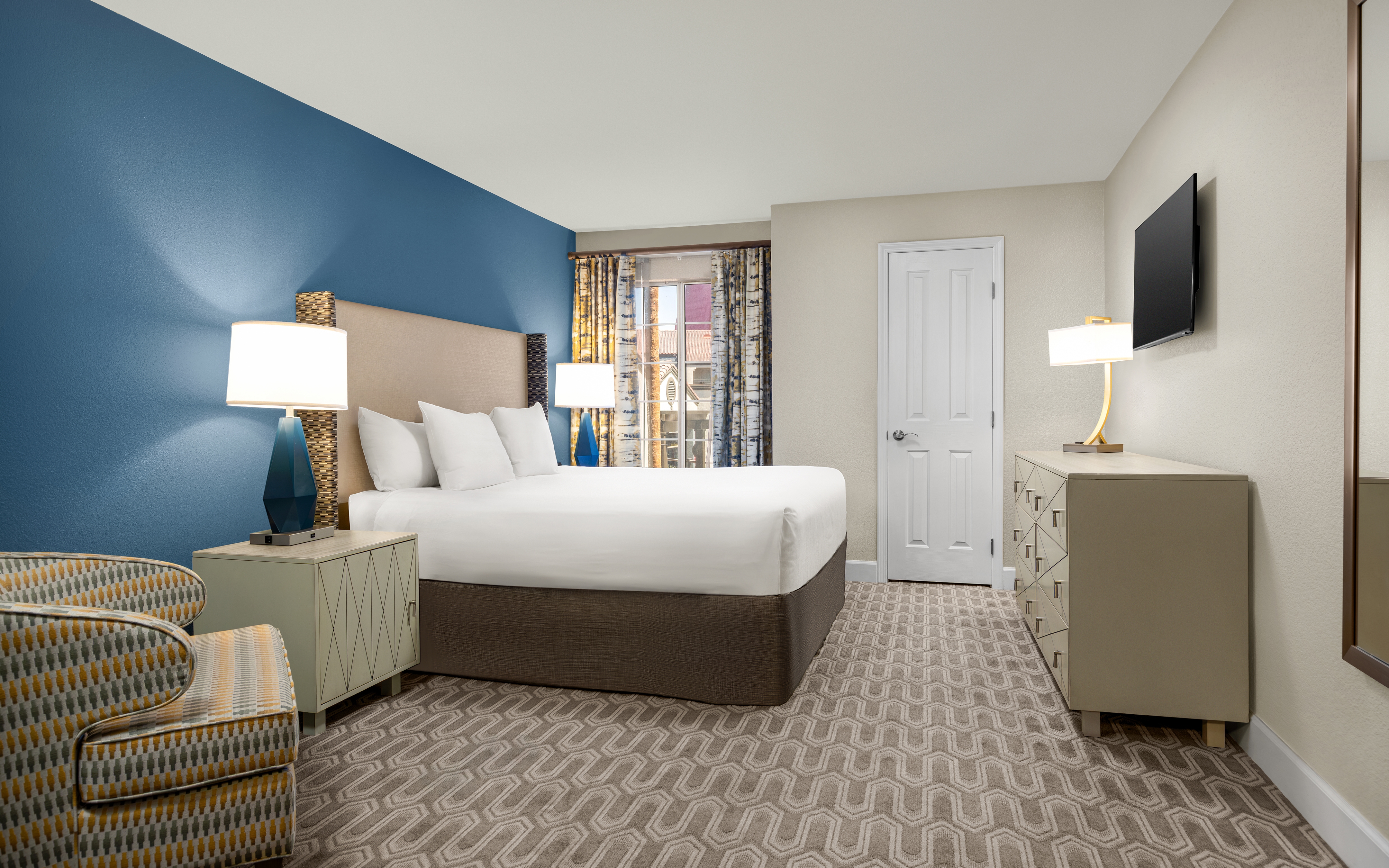 Bedroom with king bed, modern decor, and natural light.