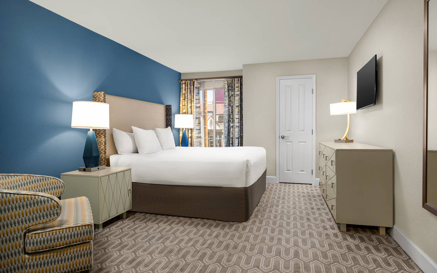 Bedroom with king bed, modern decor, and natural light.