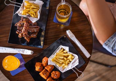 Bar food of wings, fries, and beer on a table at The Royal Sands.
