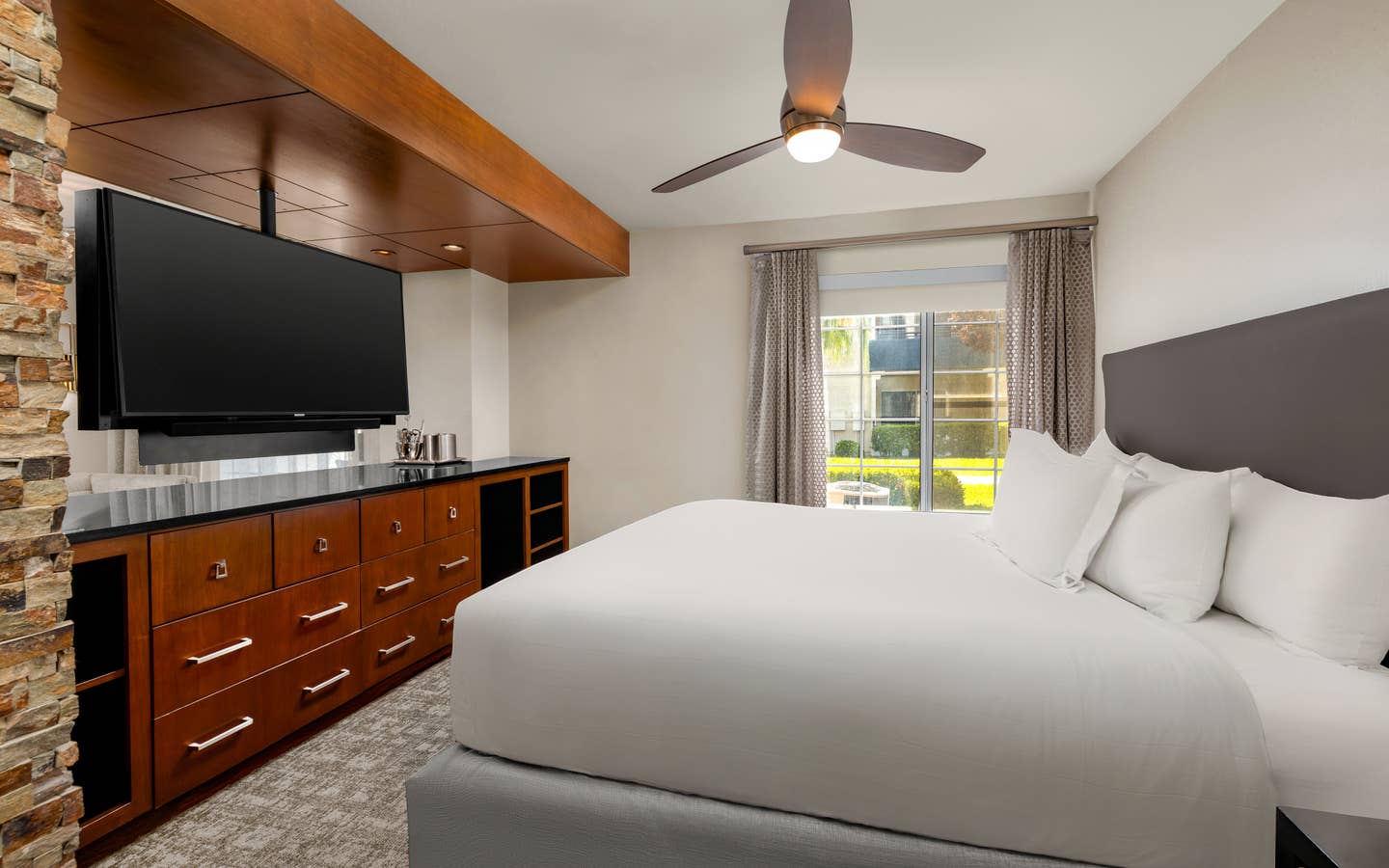 Spacious bedroom with plush bedding and modern in-room entertainment.
