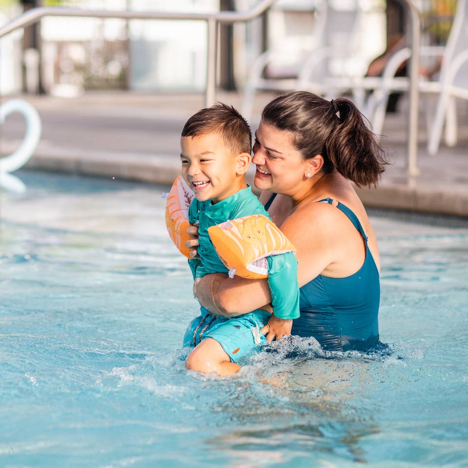 Adult holding child while laughing in resort pool at Holiday Hills Resort in Branson, Missouri.