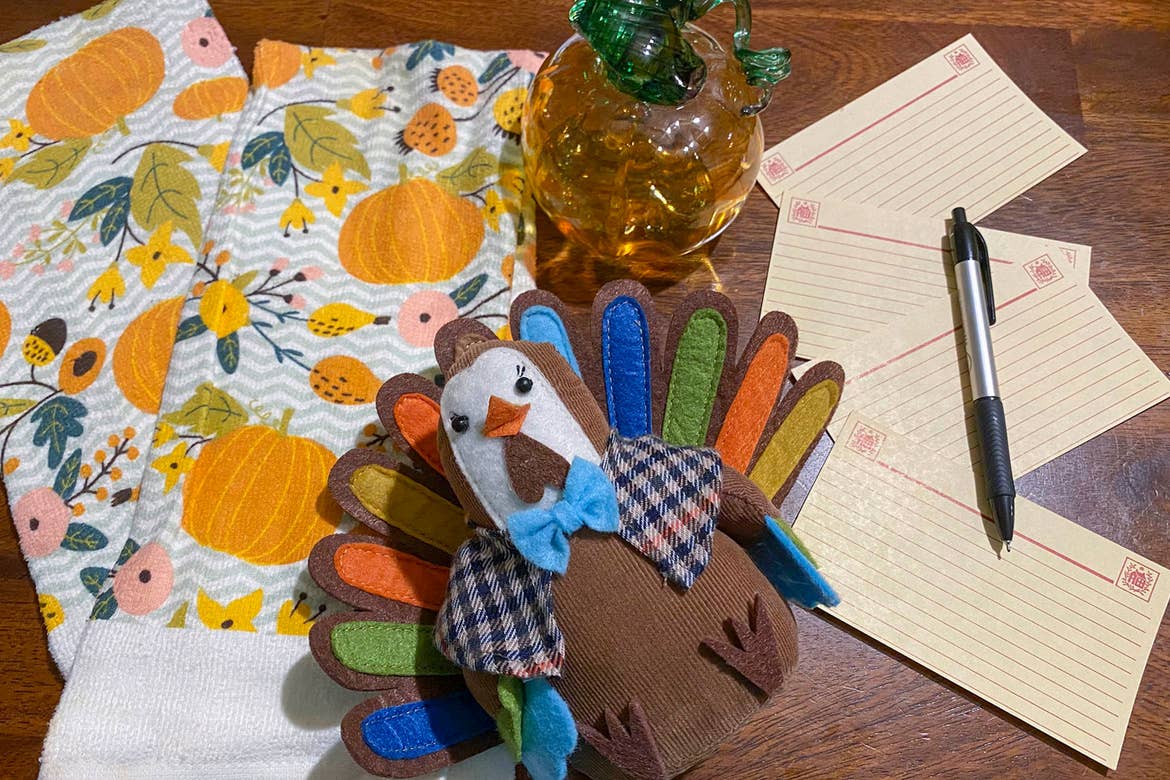 Festive towels (left) a hand-knitted turkey (middle) and recipe cards (right) are spread upon a kitchen table.