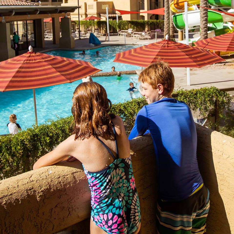 Two kids looking at pool and waterslide from balcony at Scottsdale Resort in Arizona.