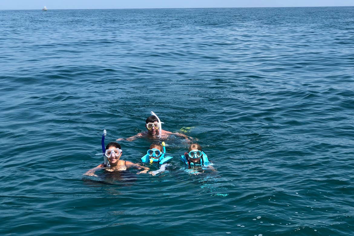 Chris Johnston (front-left), snorkels with her husband, Josh (middle-back), and two daughters, Kyler (front-middle) and Kyndall (front-right), in the ocean.
