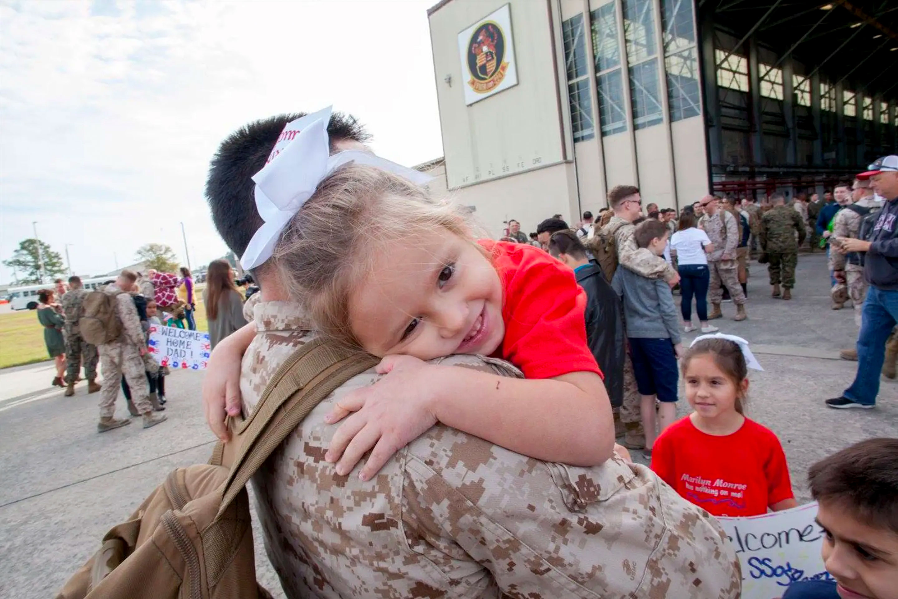 Sara Perez's youngest daughter (right) is held by her dad in his uniform outside of an air hangar.