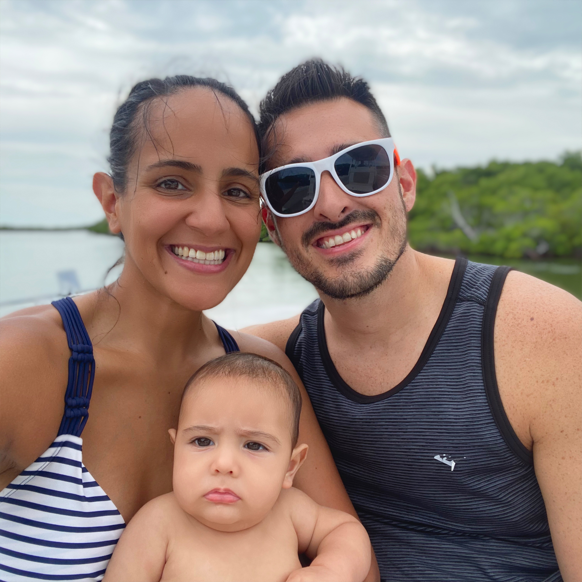 A woman, a man and an infant ride a boat on a river.