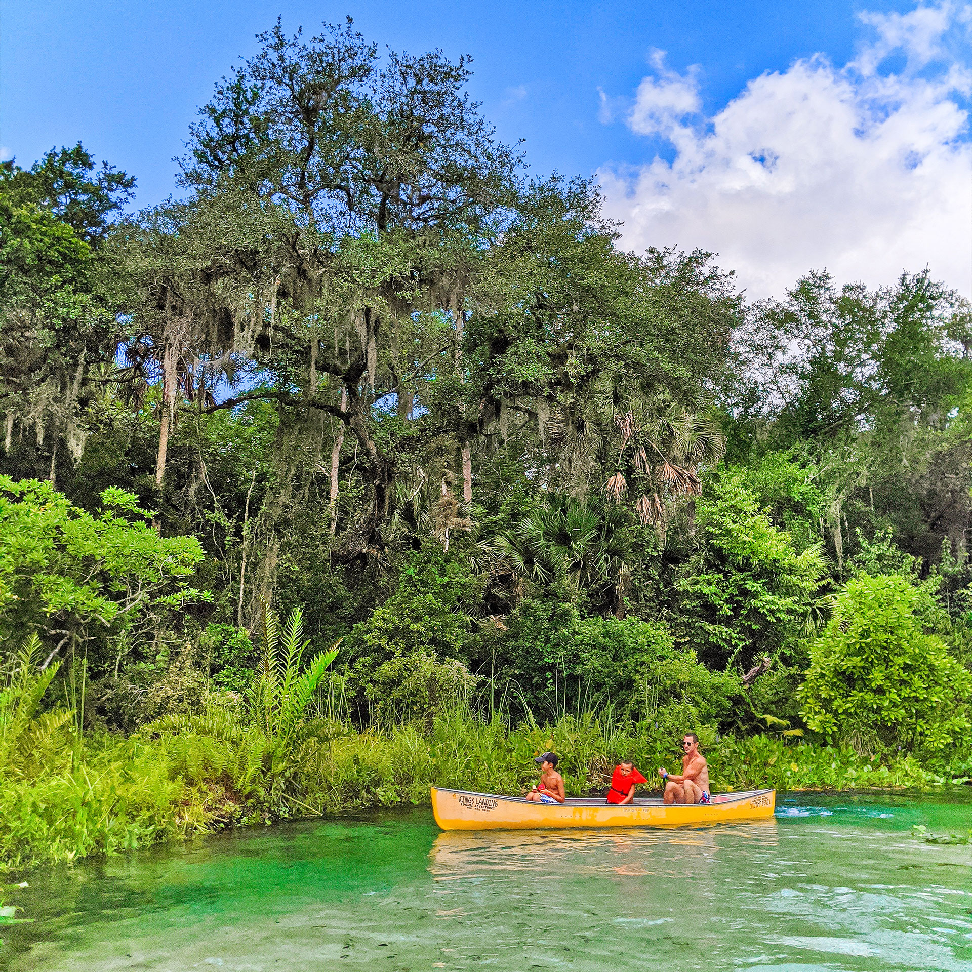 A man and two boys sit in a yellow canoe near the edge of marshland in Rock Springs.