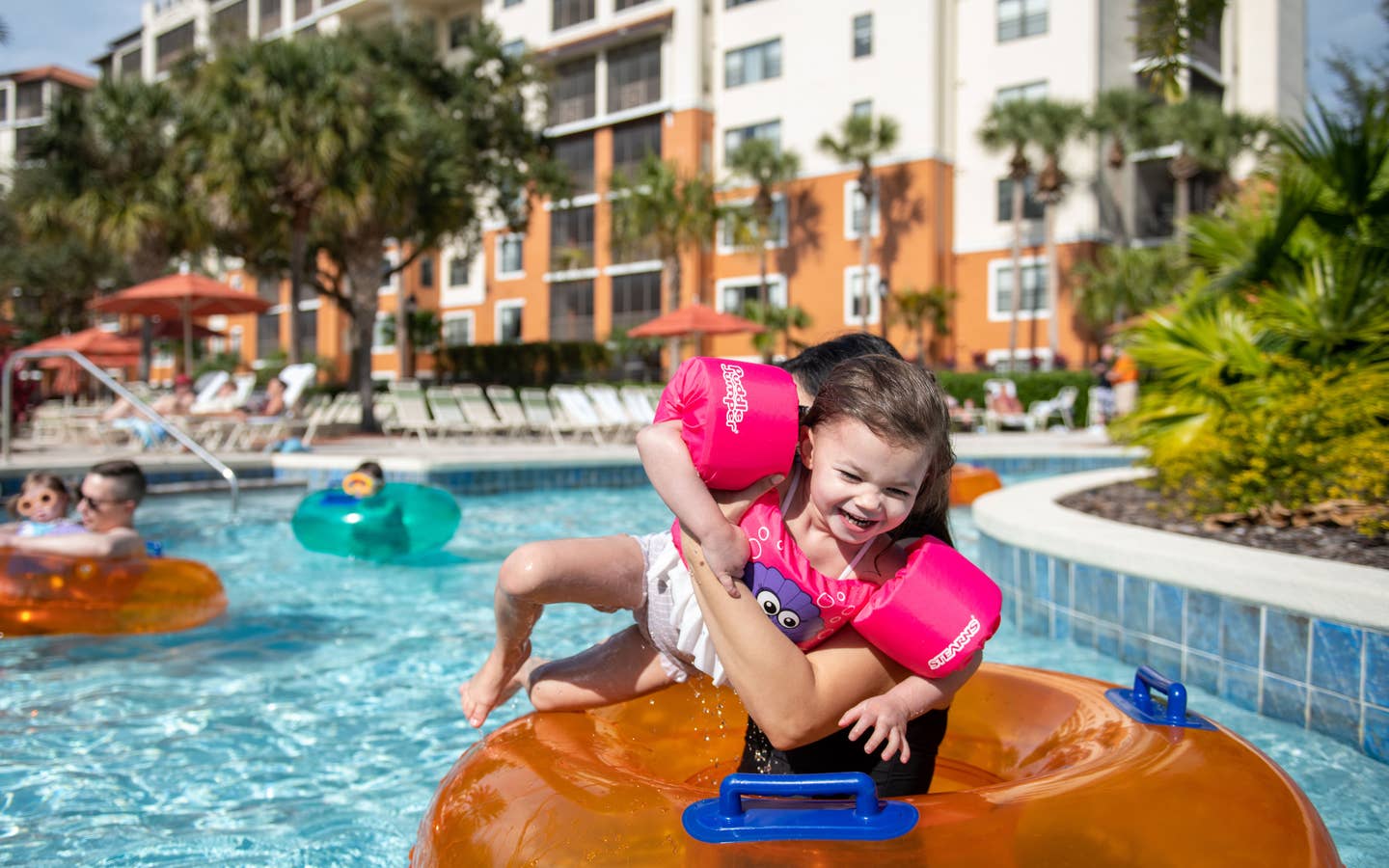 Family floating down the lazy river with inner tubes at Orange Lake Resort in Orlando, FL.