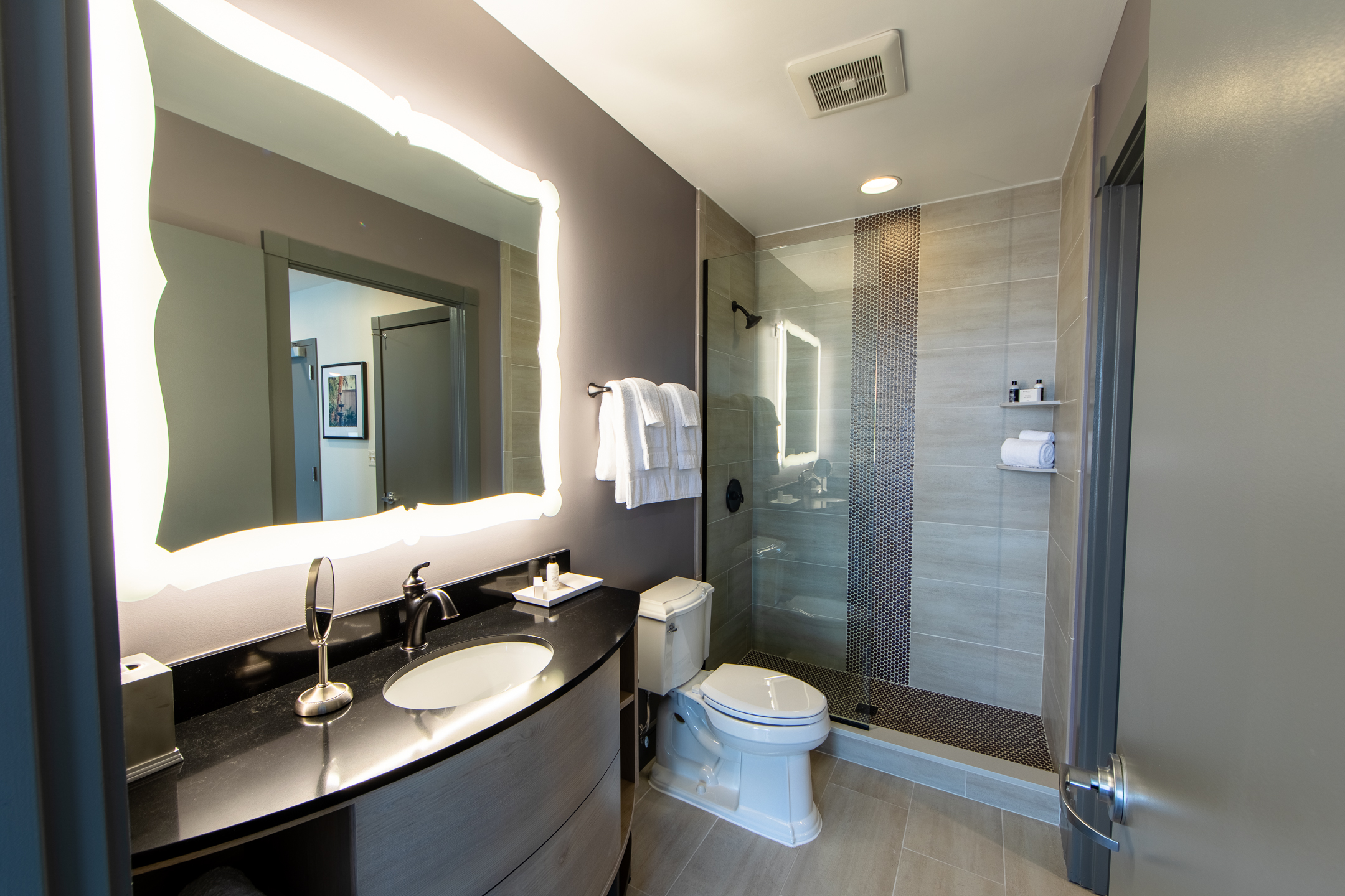 Signature Collection two bedroom villa bathroom with walk-in shower, toilet and sink with lighted mirror at New Orleans Resort in Louisiana.
