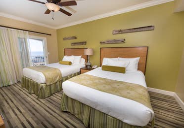 Guest bedroom with two beds and access to the balcony in a Signature two-bedroom villa at Galveston Beach Resort